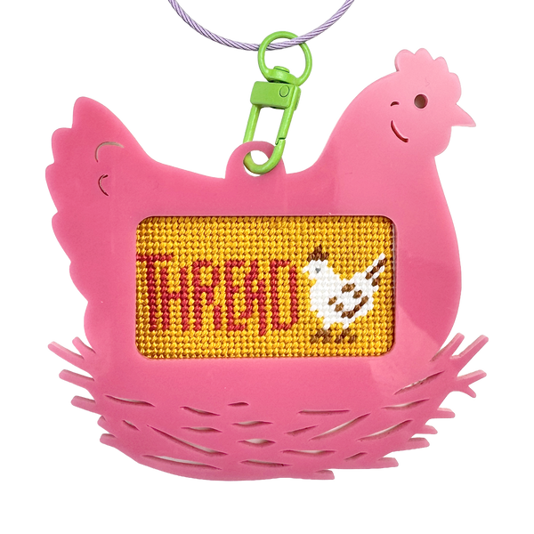 Pink chicken-shaped bag tag keychain with a yellow panel displaying text "thread" and a chicken illustration.