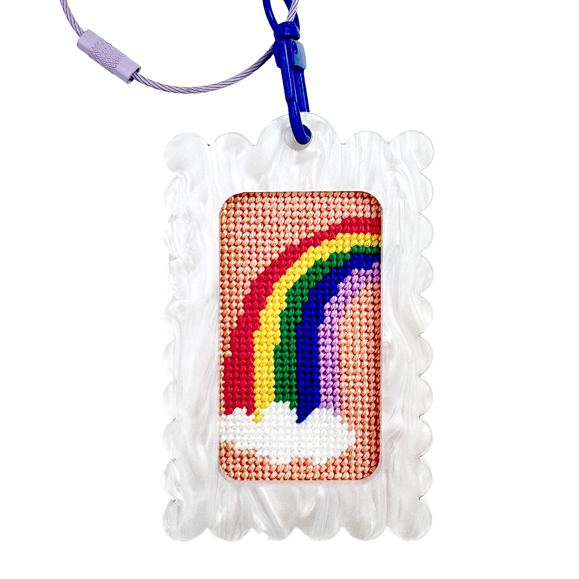 Needlepoint rainbow design in a bag tag keychain white frame with a blue clip against a white background