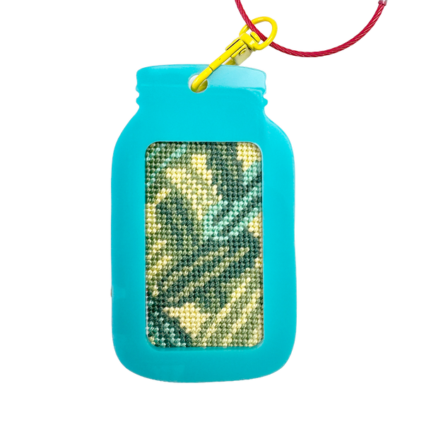 Turquoise mason jar-shaped keychain fram with a red wire and yellow clip on a white background. needlepoint design with green and yellow pickles