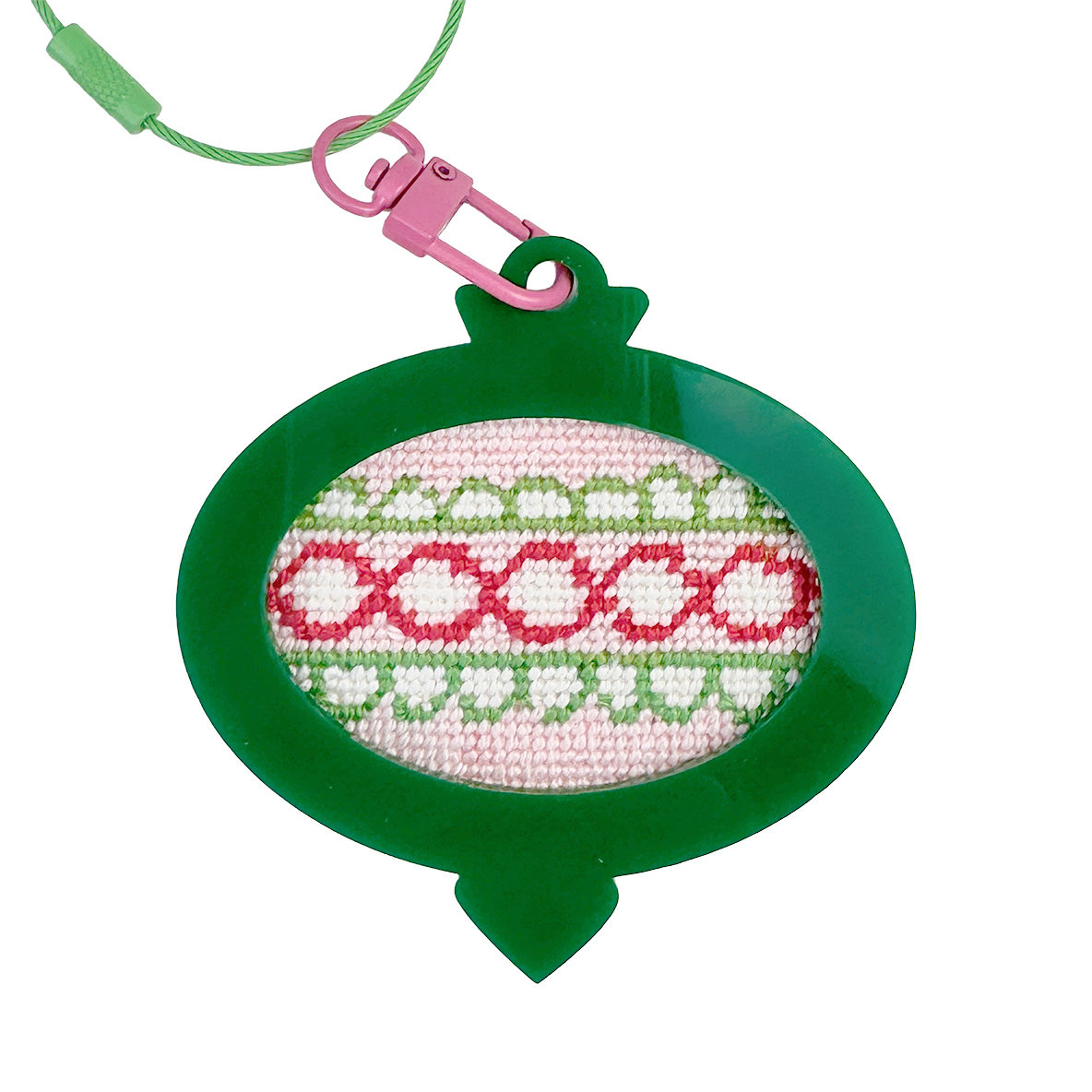 Needlepoint Christmas ornament design in a green frame with pink and white pattern on a white background