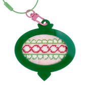 Needlepoint Christmas ornament design in a green frame with pink and white pattern on a white background